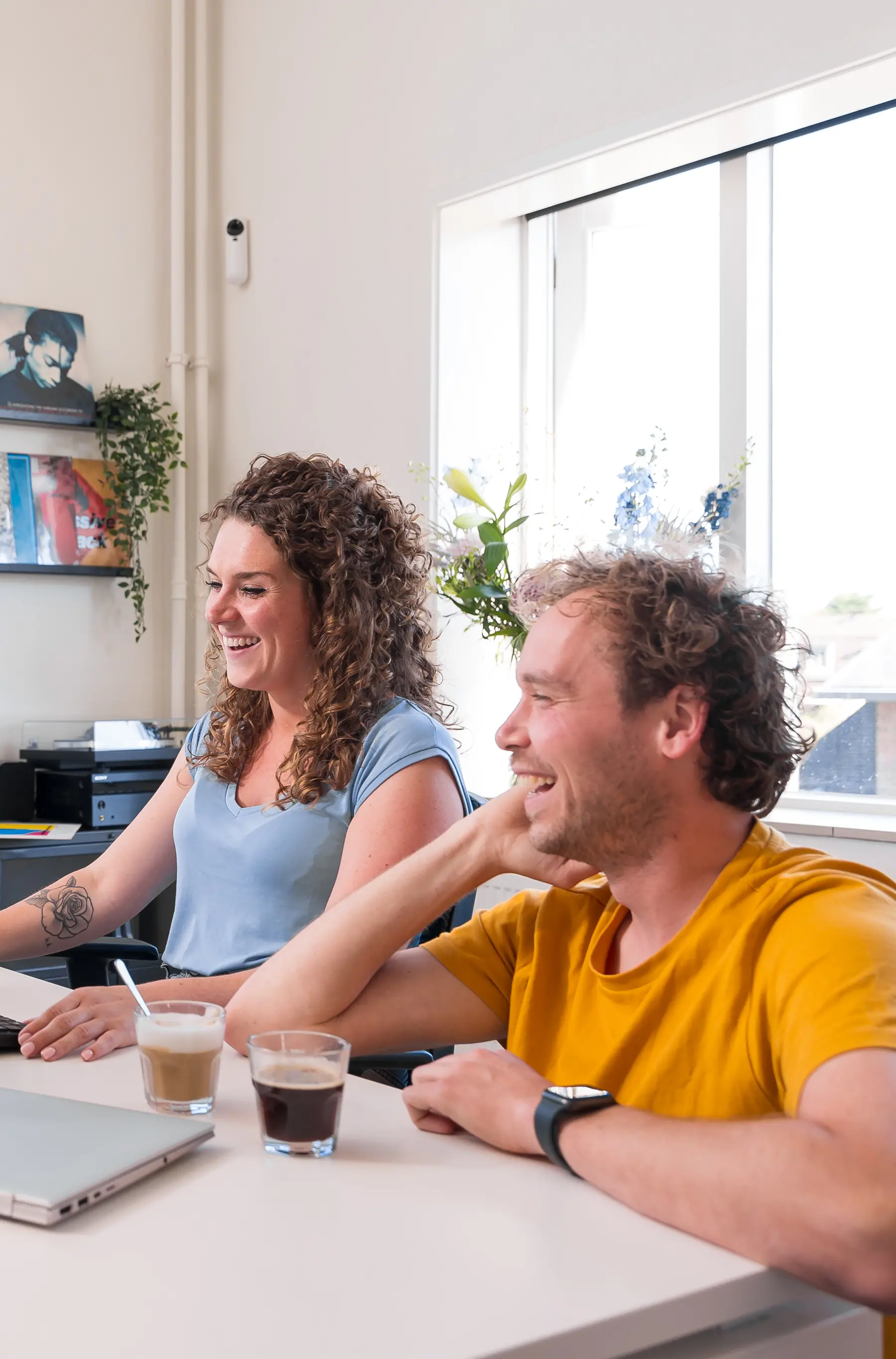 Collega's Werken Samen In Een Modern En Licht Kantoor, Lachend Achter Een Computer.